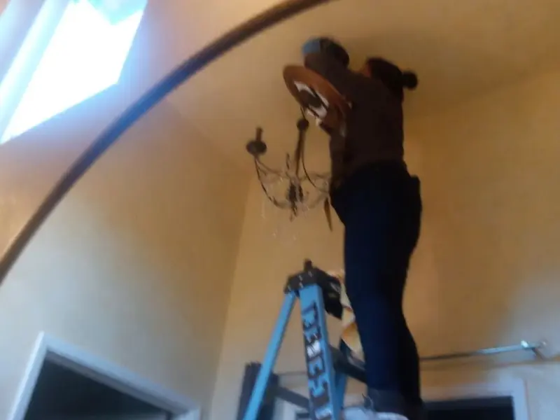 Electrician installing a chandelier in a Grantham residence